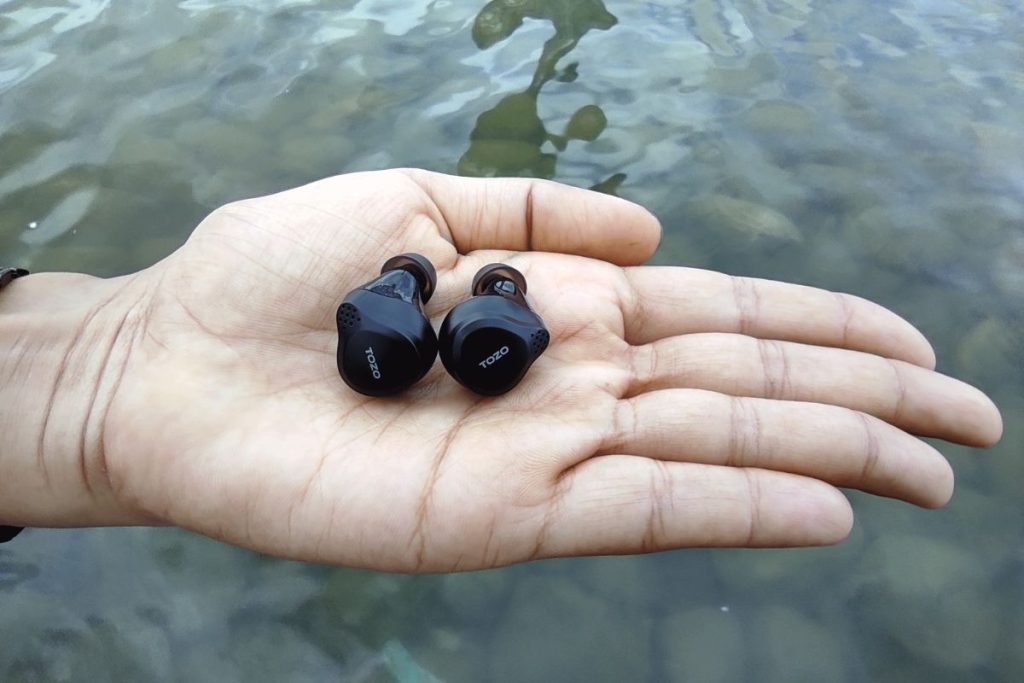 NC7 earbuds on the female palm near reservoir