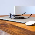 A premium desktop headphone amplifier next to open-back planar magnetic headphones on a wooden desk